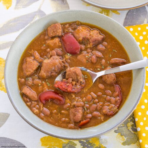 A bowl of Crock Por Pork and Bena soup on a placemat with a napkin.