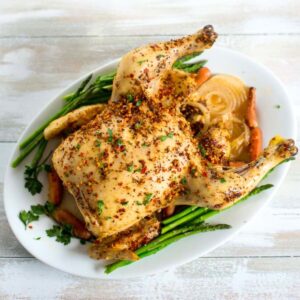 A whole cooked rotisserie chicken made in a crock pot on a serving platter.