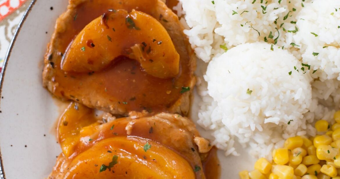 Peach Pork Chops served with rice and corn on a dinner plate.