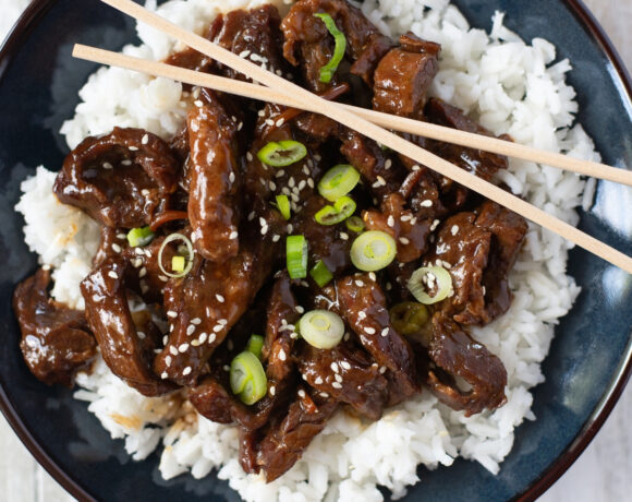 a serving of mongolian beef over white rice is a bowl