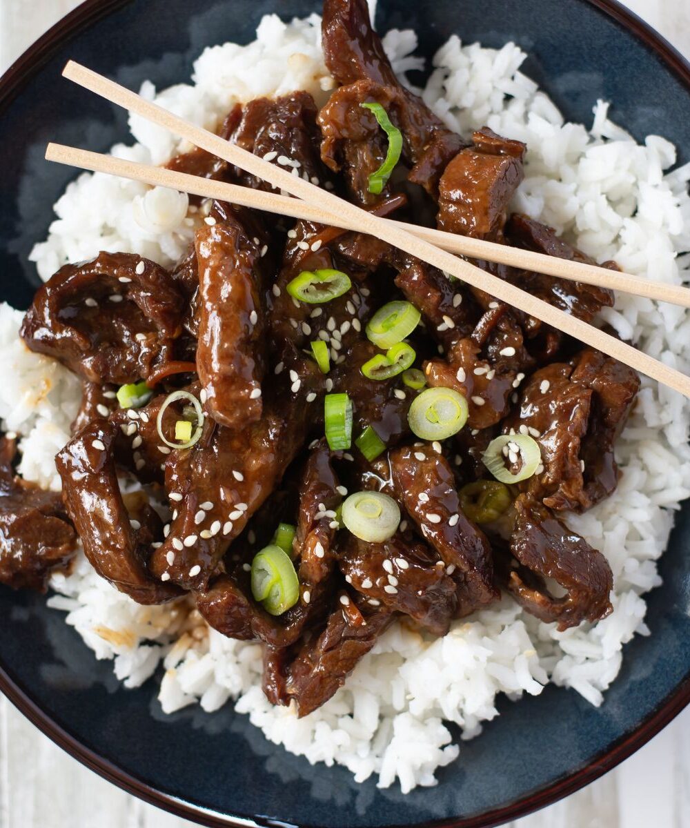 Blue bowl filled with tender Mongolian Beef served over white rice.