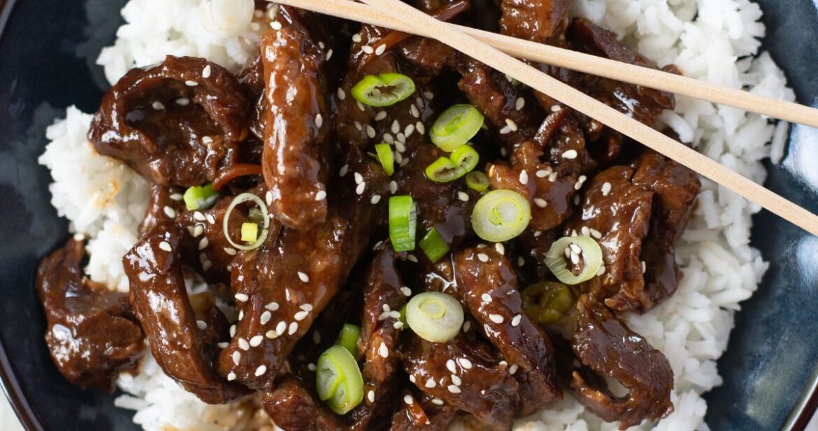 Blue bowl filled with tender Mongolian Beef served over white rice.