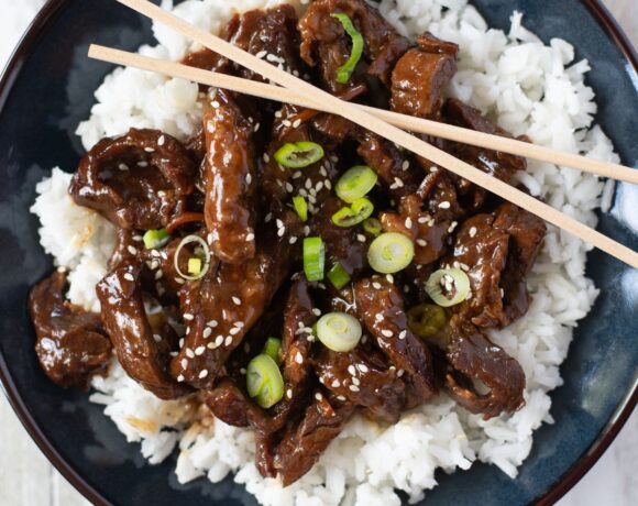 Blue bowl filled with tender Mongolian Beef served over white rice.