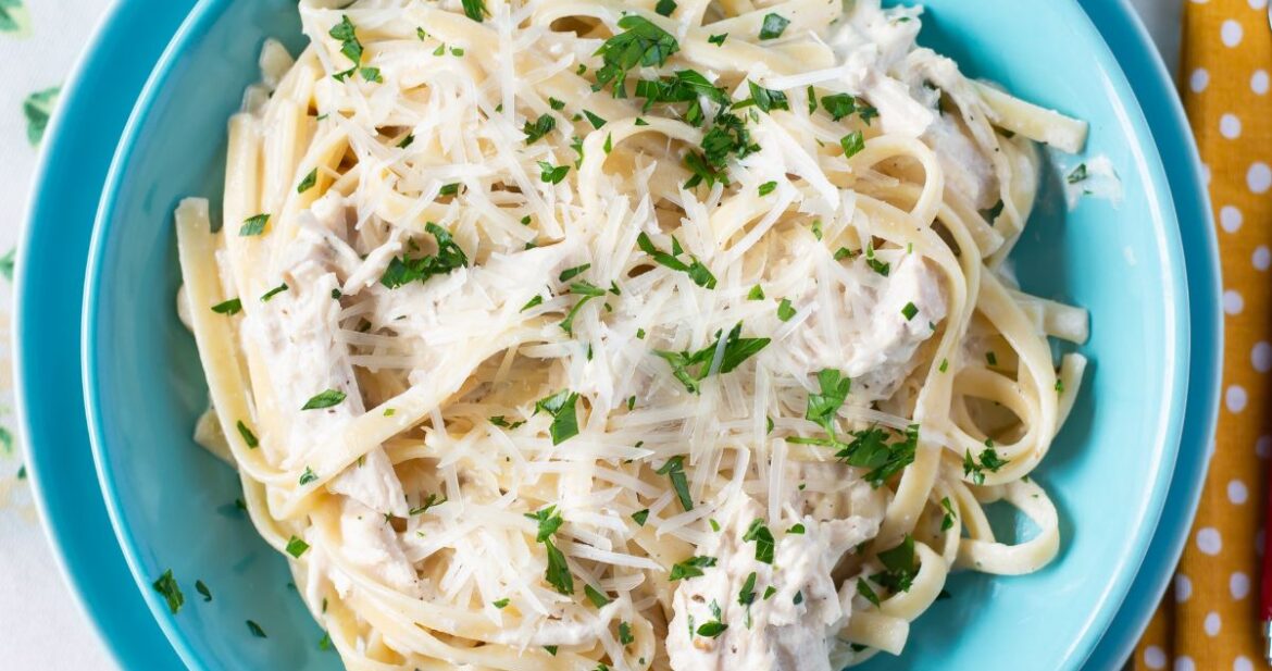 Serving Crock Pot Chicken Alfredo in a blue bowl on placemat.