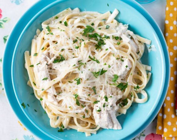 Serving Crock Pot Chicken Alfredo in a blue bowl on placemat.